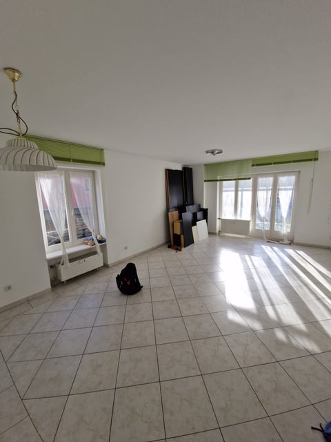 Empty apartment interior with tile flooring, green valances, white doors with windows, and cardboard boxes